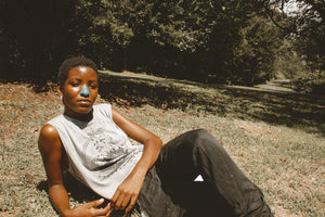 A young girl sports blue Noz sunscreen while casually laying in the grass under the sun.